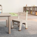A Flash Furniture wooden classroom chair with a 9" seat height next to a table.