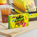 A yellow Sour Patch Kids candy box on a counter next to a drink with a straw.