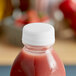 A bottle of strawberry juice with a clear tamper-evident cap on a counter.