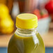 A yellow tamper-evident cap on a bottle of green juice.