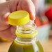 A hand holding a plastic bottle of green liquid with a yellow tamper-evident cap.