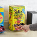 A hand holding a black box of Sour Patch Kids with different colored characters.
