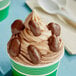 A cup of ice cream topped with Albanese milk chocolate covered pecans.
