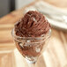 A scoop of I. Rice Marshmallow Variegate on chocolate ice cream in a glass.