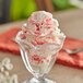 A glass bowl with a scoop of I. Rice strawberry variegate ice cream.