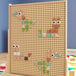 A wooden peg board with different colored shapes including pastel colors.