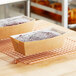 Two brown bread loaves in Tielman Bake-Well paper containers on a cooling rack.