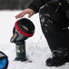 A person in black pants using a Mr. Heater Little Buddy portable propane heater to warm their feet in an outdoor setting.