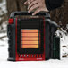 A person holding a Mr. Heater Portable Buddy outdoor liquid propane heater in the snow.