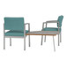 Two Lesro Lenox steel arm chairs with blue cushions and a table with a laminate top.