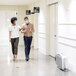 A man and woman walking down a hallway with a Fellowes AeraMax Pro air purifier.