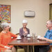 A group of people sitting at a table in a hospital cafeteria with a Fellowes AeraMax Pro air purifier on the wall.
