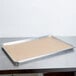 A Baker's Lane unbleached Quilon-coated parchment paper sheet with brown dough on a tray on a counter.