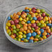 A bowl of Natural Rainbow Chocolate Gems on a table.
