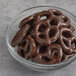 A glass bowl of dark chocolate covered pretzels.