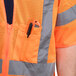 A person wearing an orange Cordova class 3 high visibility safety vest with a pocket containing a pen.
