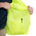 A person holding a lime Cordova Class 3 high visibility mesh safety vest with a pocket.