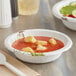 A Dixie Ultra paper bowl with soup and a spoon on a table.