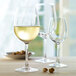 A Stolzle Weinland Bordeaux wine glass filled with white wine on a table with a pistachio.