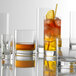 A group of Stolzle New York Rocks glasses filled with different colored drinks.
