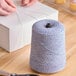 A large cone of blue and white variegated polyester cotton blend baker's twine.