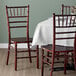 A Lancaster Table & Seating mahogany Chiavari chair at a table with a white tablecloth.
