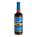 A Torani 750 mL glass bottle of chocolate macadamia nut syrup on a table.
