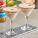 Two glasses of white liquid with Torani Cupcake flavoring and sprinkles on top.