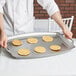 A person holding a Vollrath griddle pan with pancakes on it.