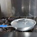 A Vollrath Wear-Ever aluminum non-stick fry pan with a blue Cool Handle on a stove.