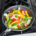 A Vollrath Wear-Ever aluminum non-stick fry pan filled with vegetables on a stove top.