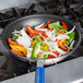 A Vollrath Wear-Ever non-stick fry pan filled with vegetables cooking on a stove.