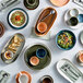 A table with white Acopa china bowls and plates on it.