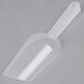 A clear plastic scoop with a handle on a gray surface.