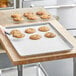 A person using a Baker's Mark parchment paper sheet to line a cookie sheet.
