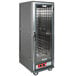 A gray Metro C5 heated holding cabinet with clear doors on wheels and shelves.