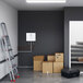 A white room with a ladder next to a box with a black and white label.