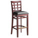 A Lancaster Table & Seating mahogany wood bar stool with a black cushioned seat.