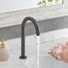 A person washing their hands under a Waterloo deck-mount hands-free faucet.