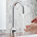 A person washing their hands under a Waterloo deck-mount hands-free sensor faucet with a gooseneck spout.