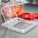 A Cambro clear plastic FlipLid on a red plastic food container with a red spoon inside.
