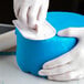 A person using an Ateco white plastic cutter to cut blue cake.