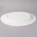 A white oval porcelain platter with a rim on a gray surface.