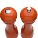 Two Chef Specialties butternut orange pepper mills with silver tops and a salt shaker.