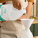 A woman using a white funnel to pour Noble Chemical Novo foaming hand sanitizer into a plastic container.