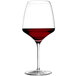 A Stolzle burgundy wine glass full of red wine.
