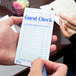 A person holding a green and white paper guest check with lines for the top guest receipt.