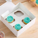 A white box with three cupcakes decorated with blue frosting, each placed in a designated slot, with one slot remaining empty.