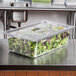 A Vollrath clear plastic food pan filled with lettuce and greens on a table.