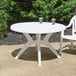 A white Grosfillex table on an outdoor patio.